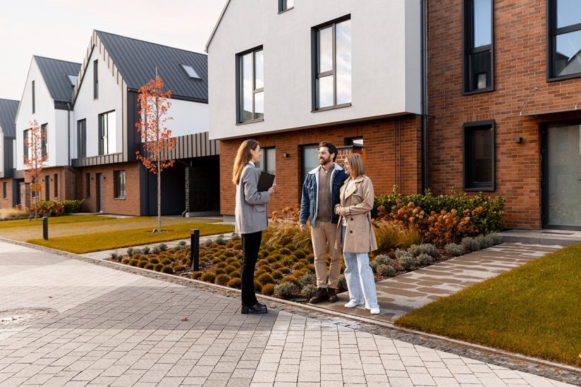 Makelaarsgesprek bij moderne nieuwbouwwoningen met stel en adviseur
